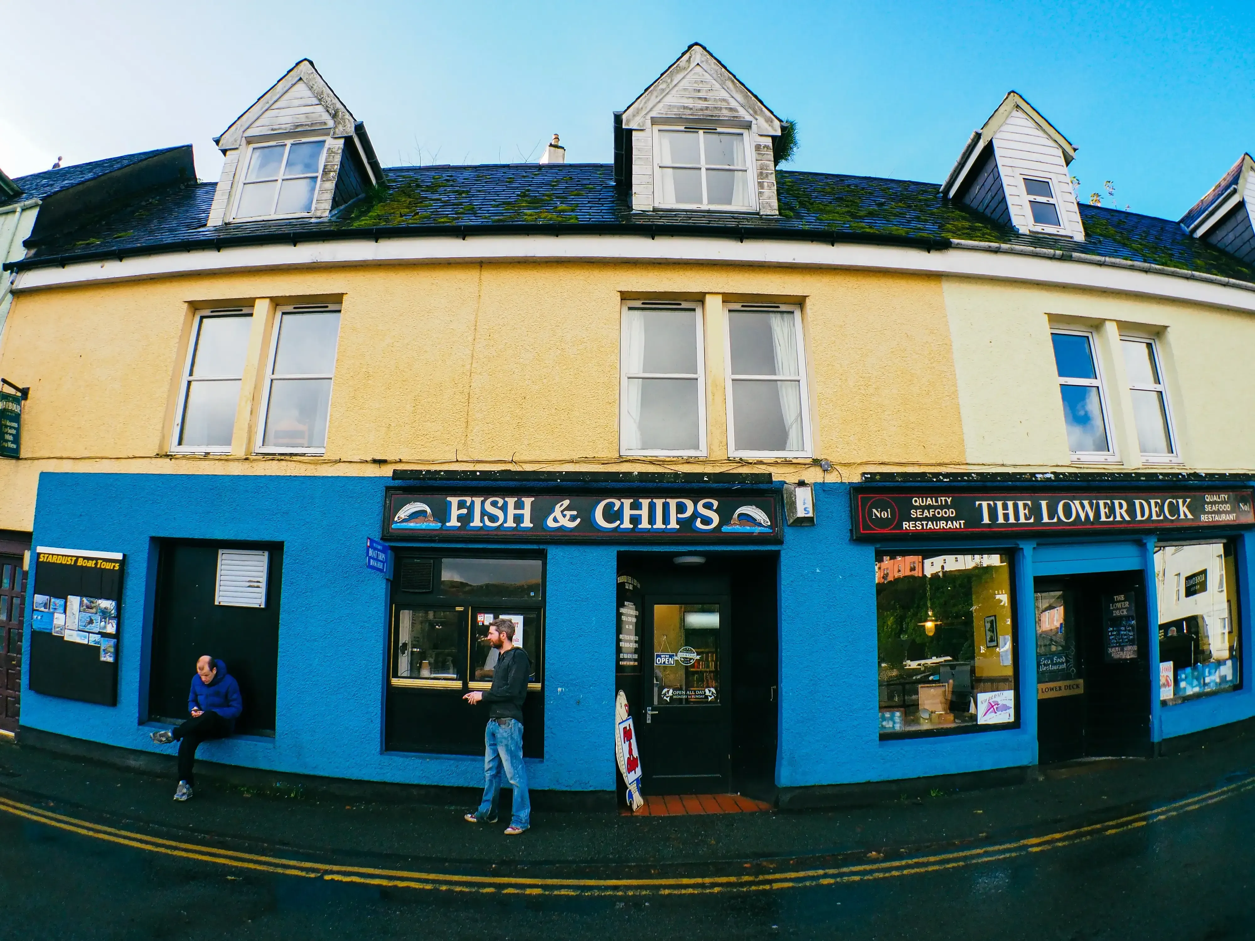 Wide-angle (fisheye) photo of a colorful fish and chips shop in Portree harbor.
