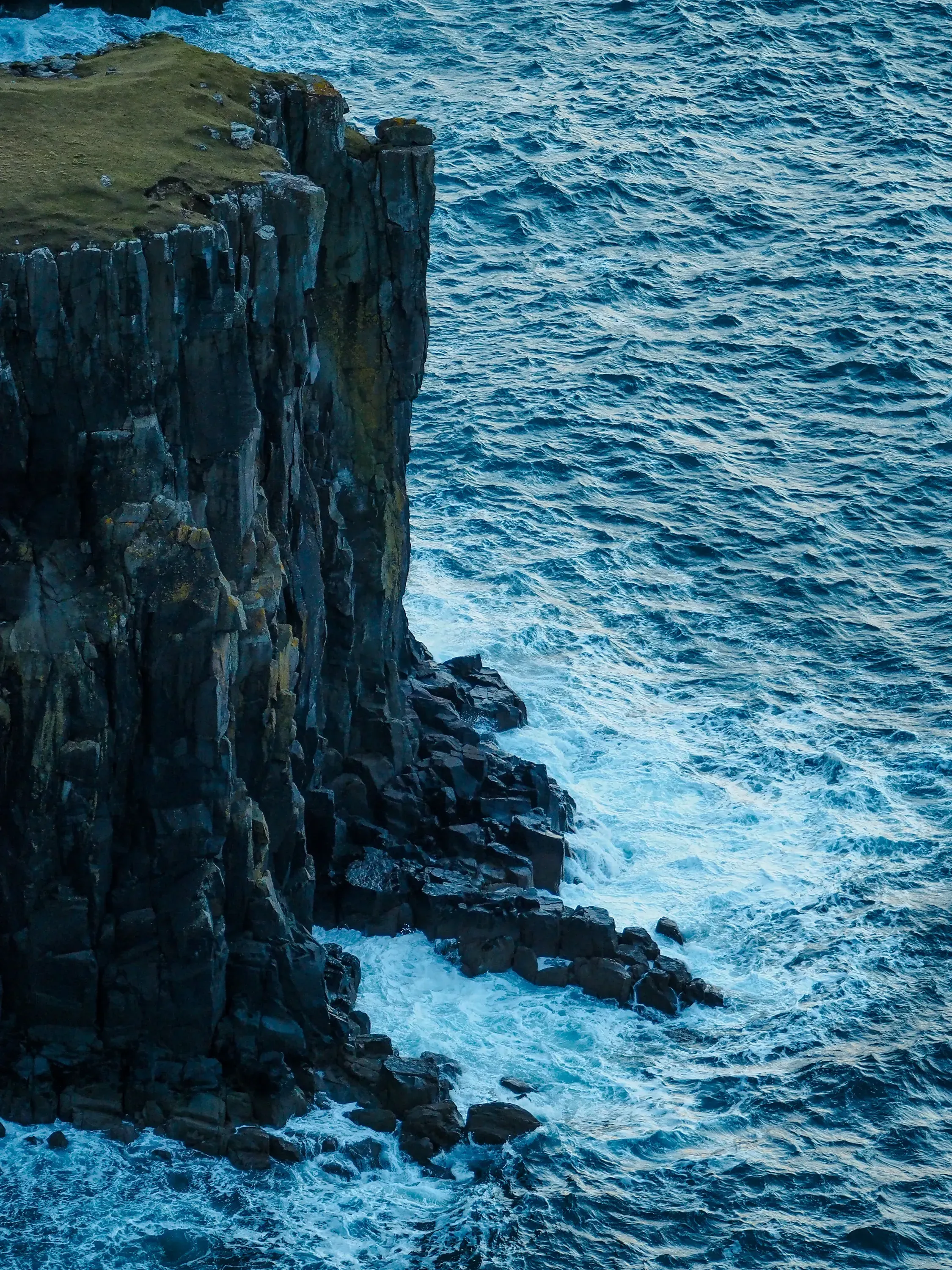 Dramatic, steep sea cliff dropping sharply to the water below.