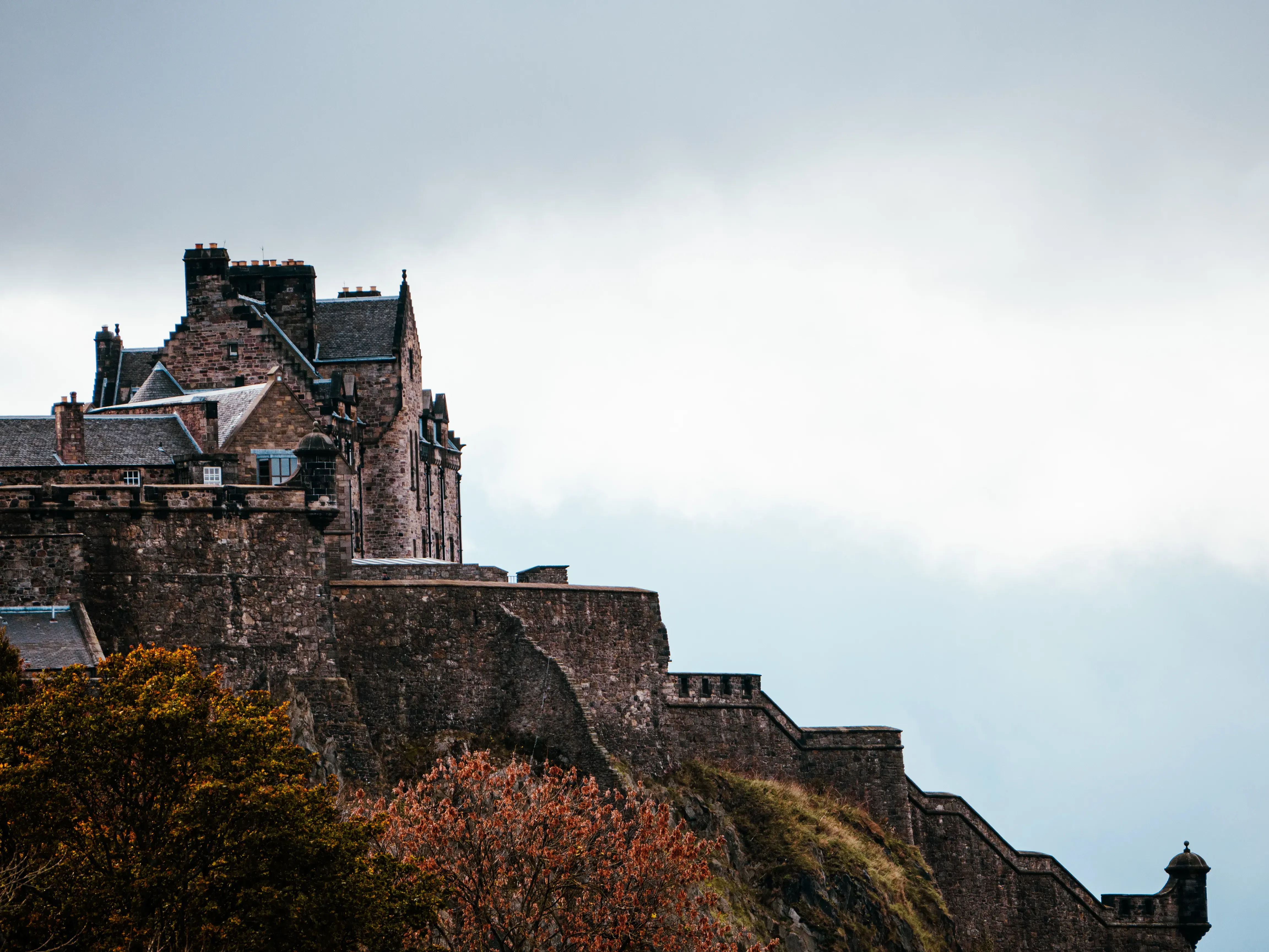 Side view of the fortified walls and rock face supporting Edinburgh Castle.