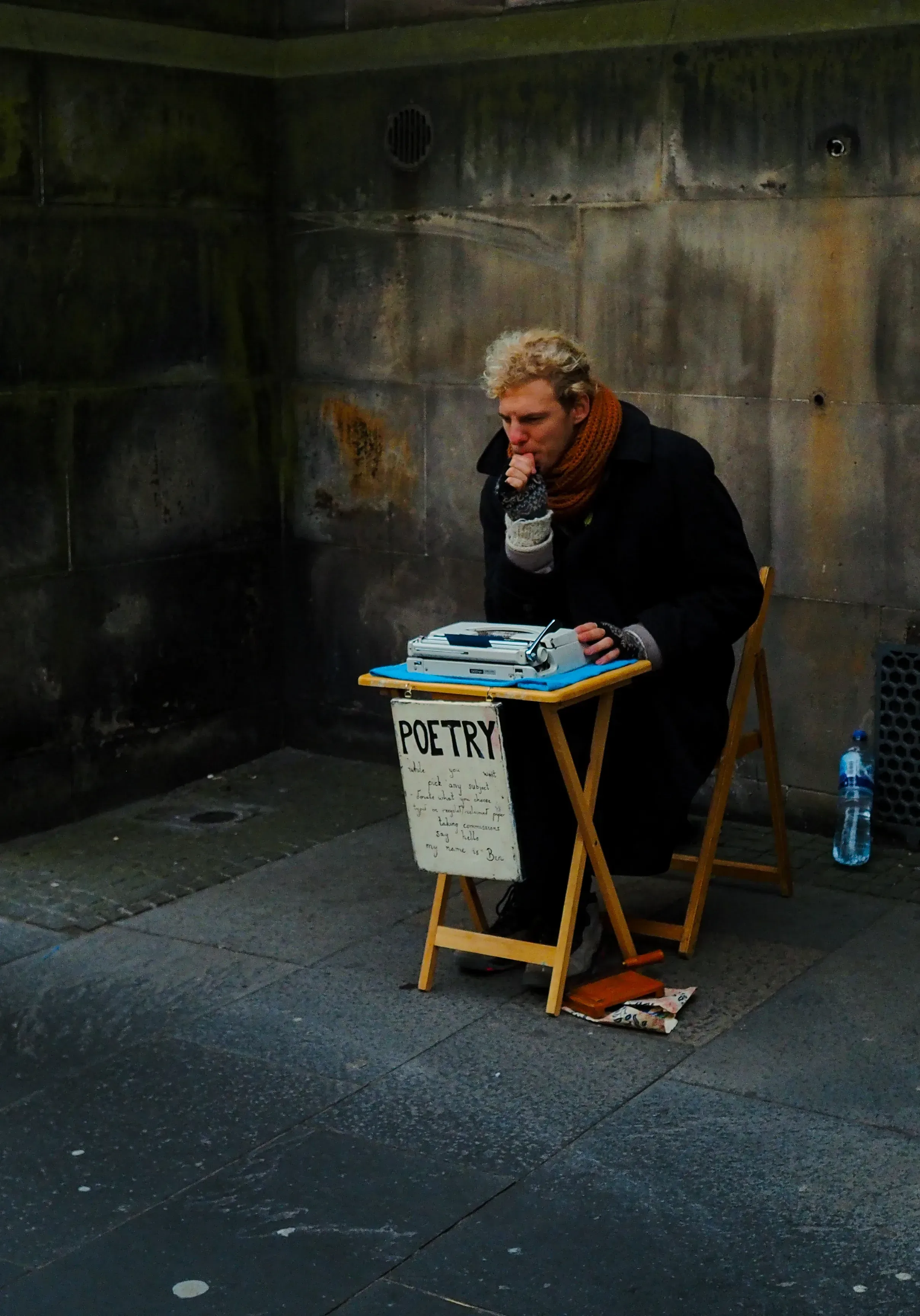 Street poet sitting or standing, writing or performing in a public area.