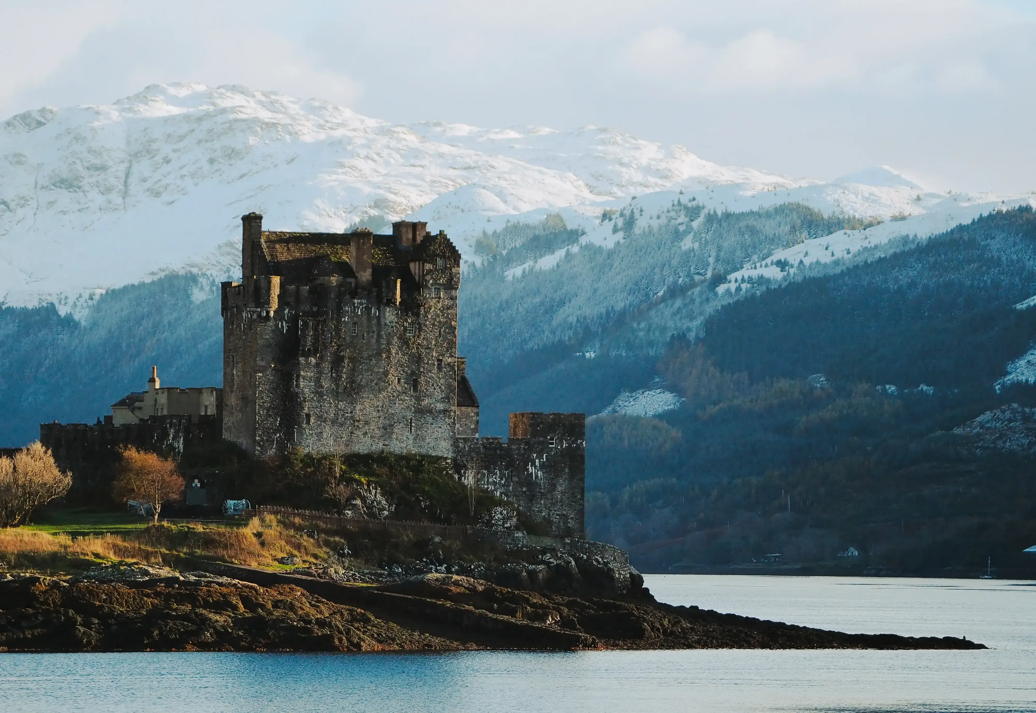 Ancient stone castle ruins (e.g., Dunvegan Castle) set against the dramatic backdrop of the Isle of Skye.