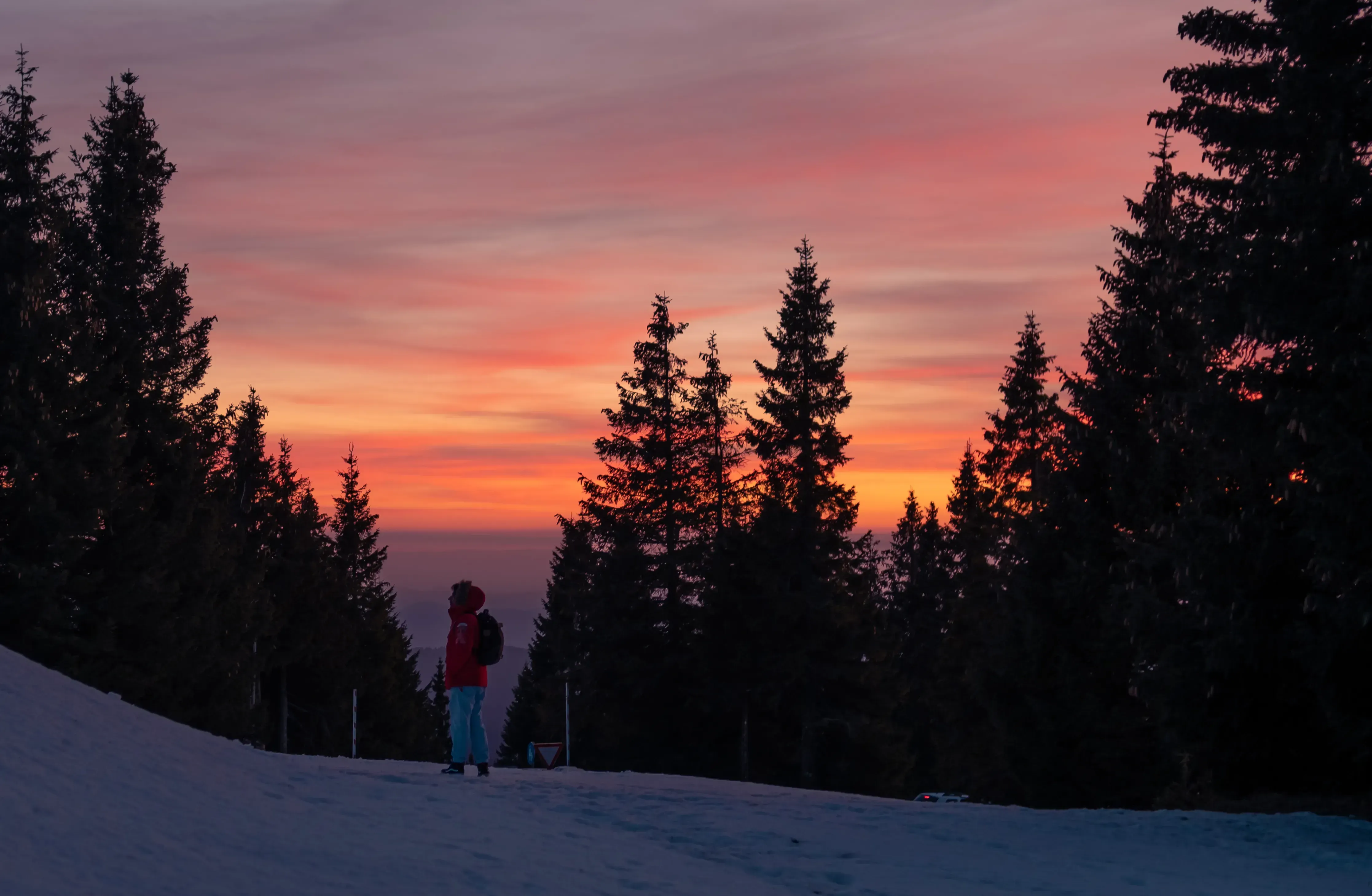Iair standing in the high-altitude landscape of Rogla, silhouetted against the bright colors of the sunset.