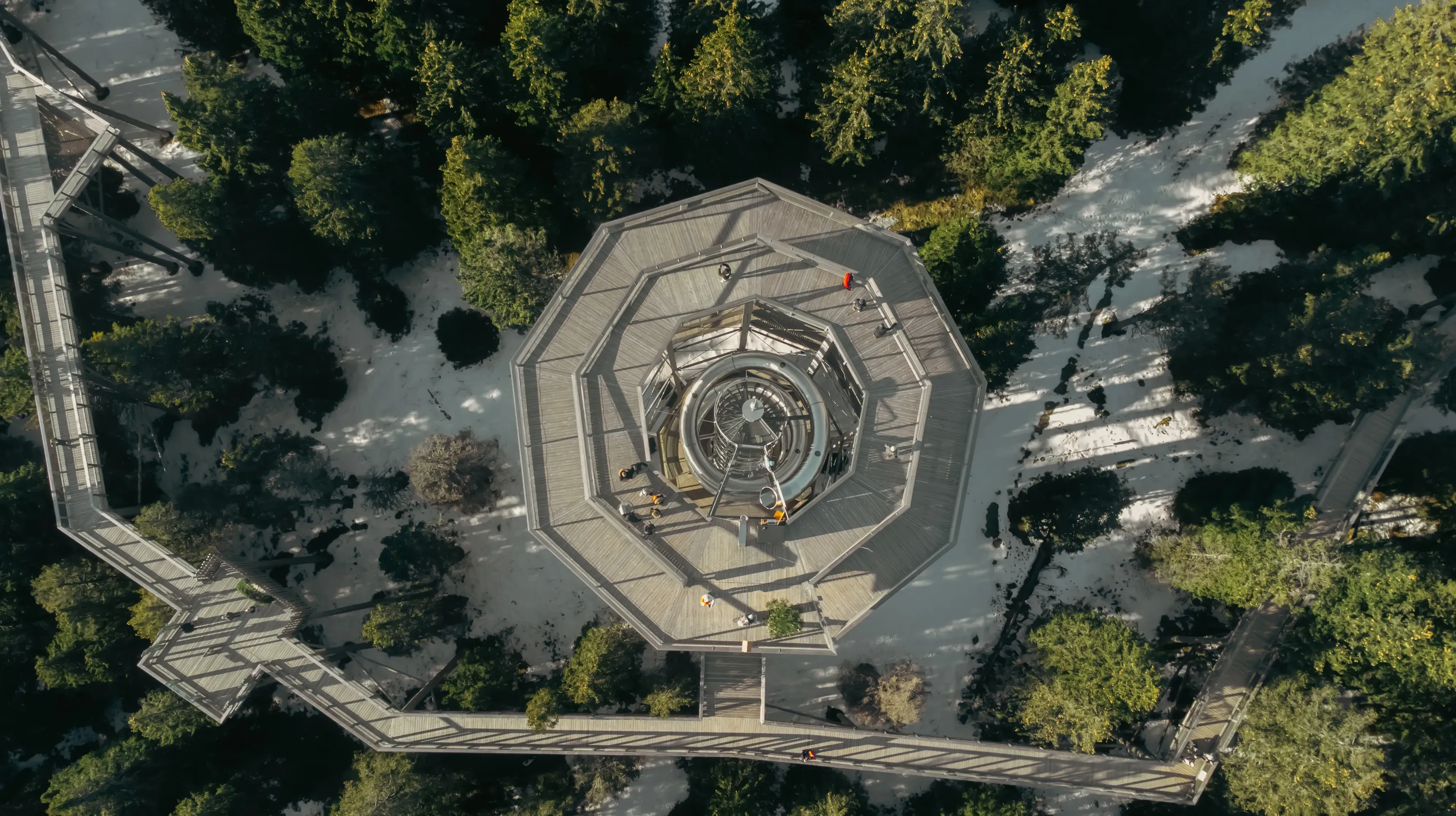 High-angle drone shot of the long, enclosed spiral slide descending from the Treetop Walk at Rogla.