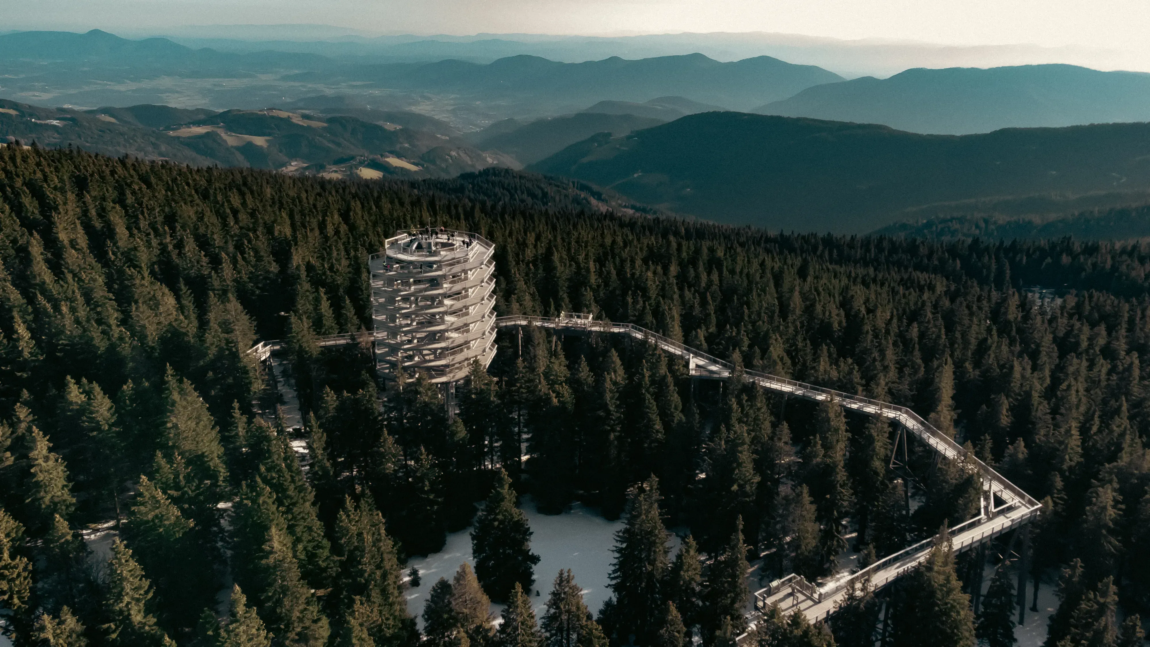 Aerial drone view showing both the winding wooden treetop walkway and the attached recreational slide near Rogla.