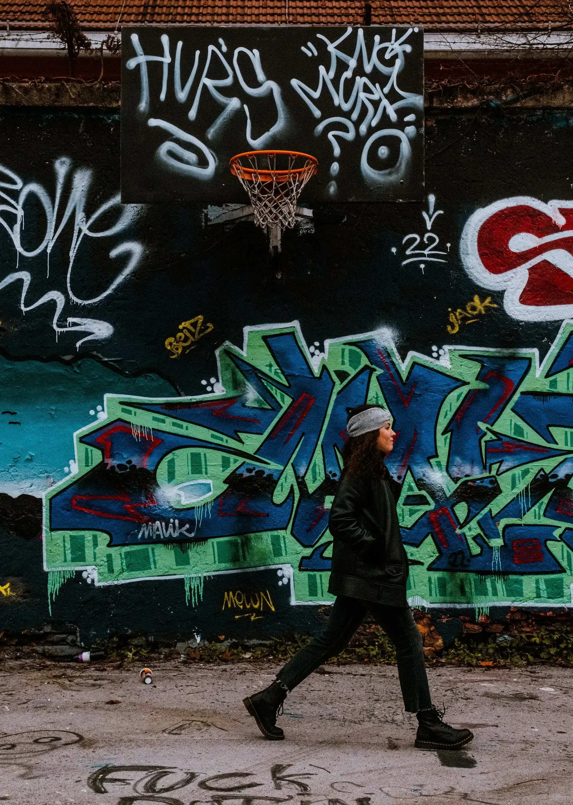 Beatrice walking past (passing by) the vibrantly painted and decorated buildings of Metelkova Mesto.