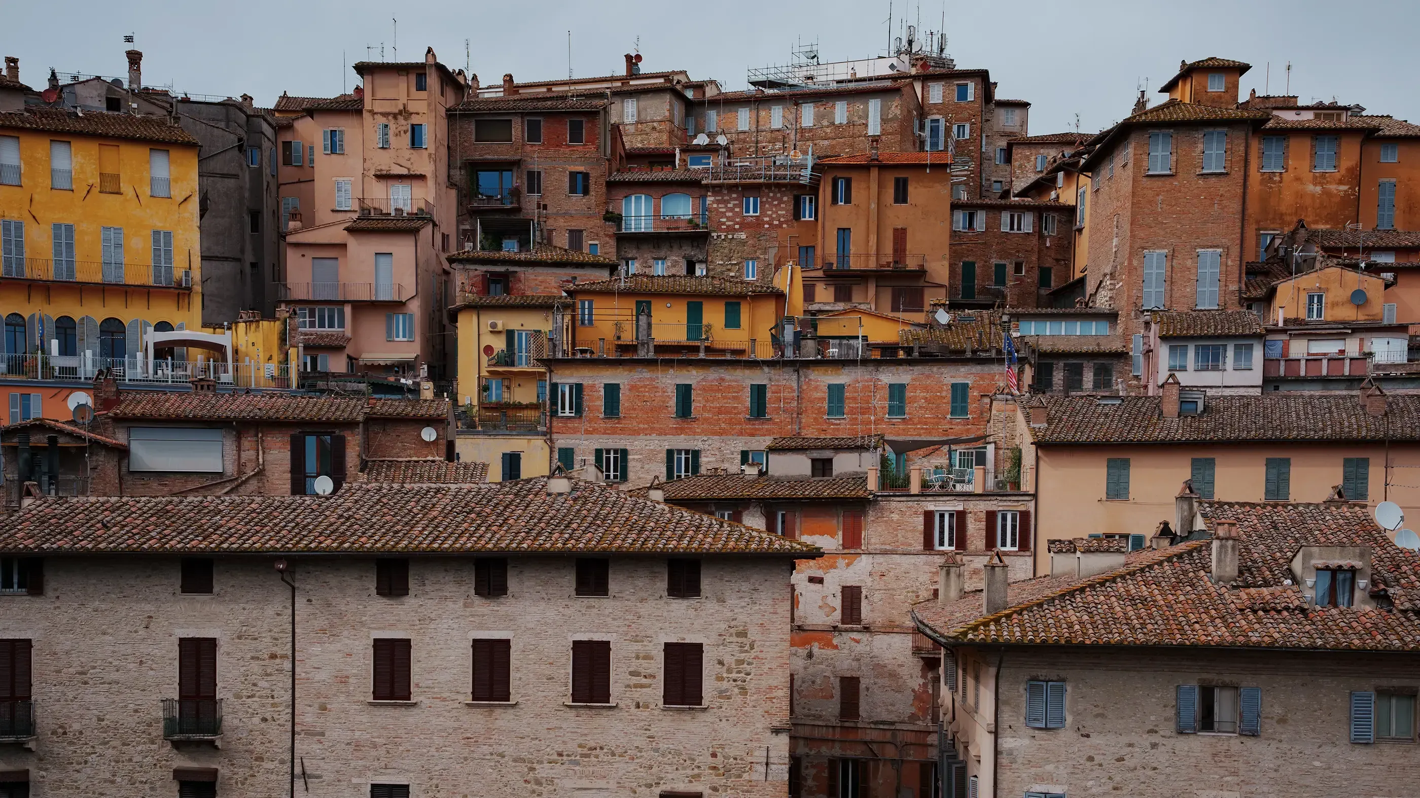 View of the city of Perugia, featuring traditional yellow and orange buildings on the hillside.