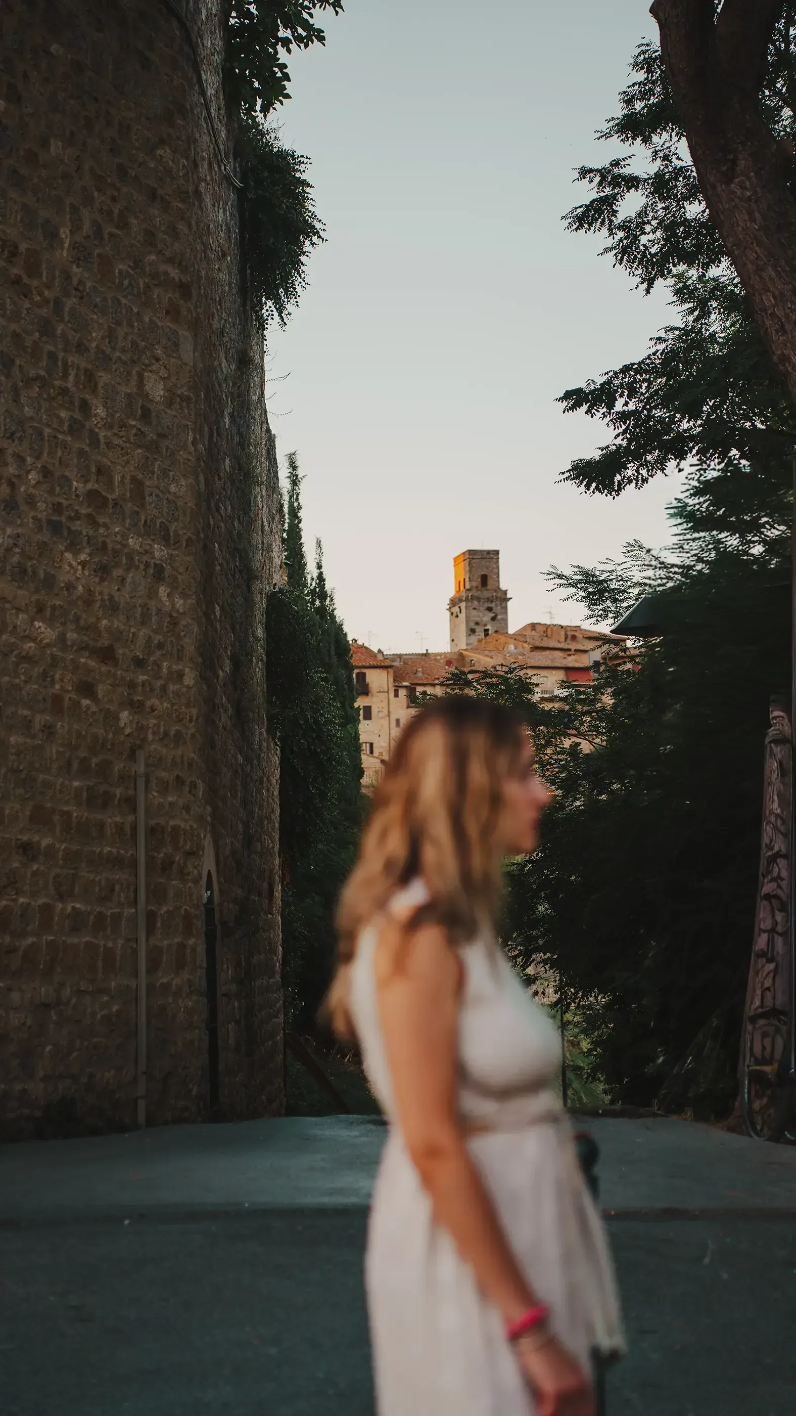 Out-of-focus photo of Letizia with a distinct medieval tower (San Gimignano) sharp in the background.