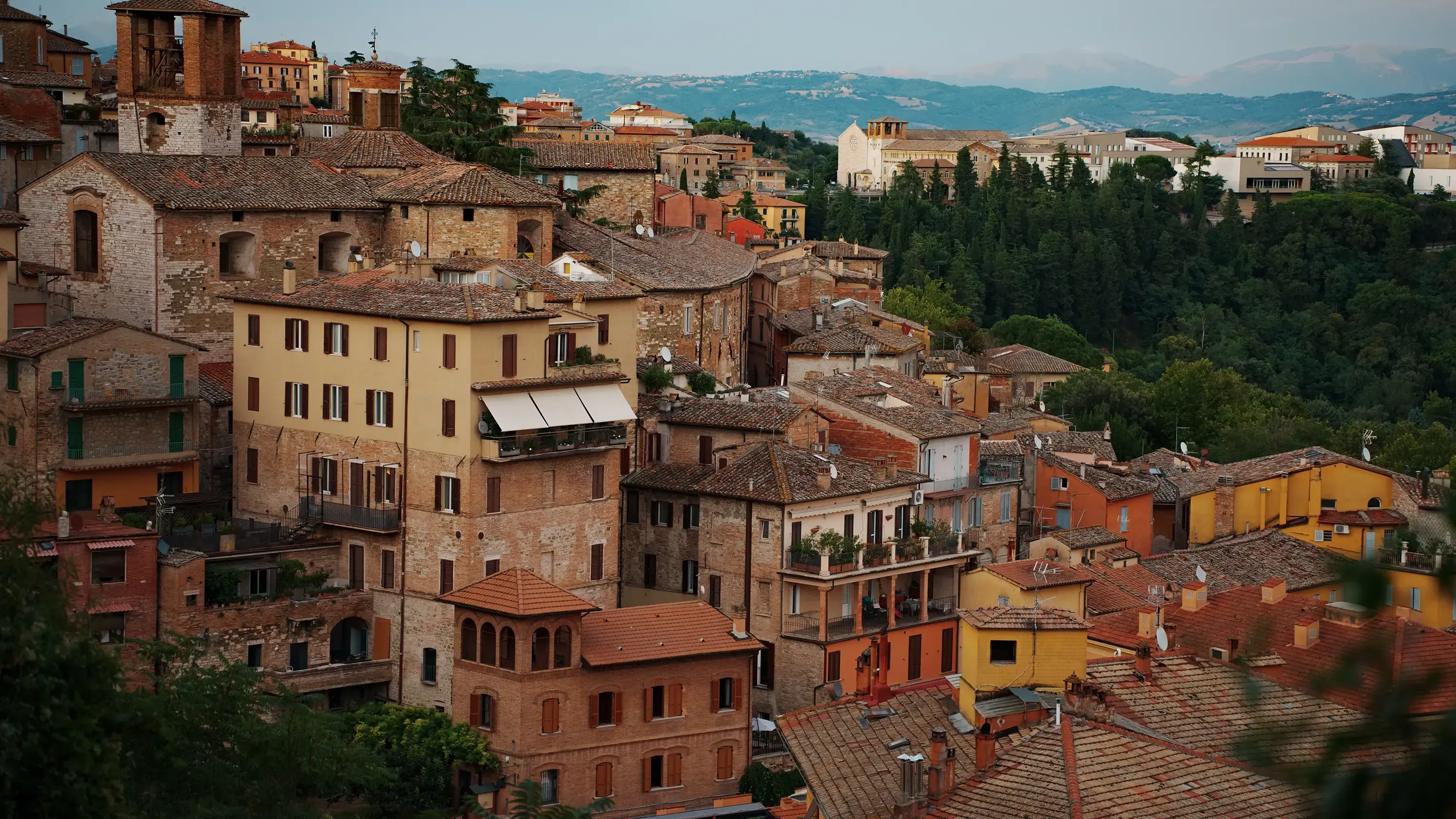 View of the city of Perugia, featuring traditional yellow and orange buildings on the hillside.