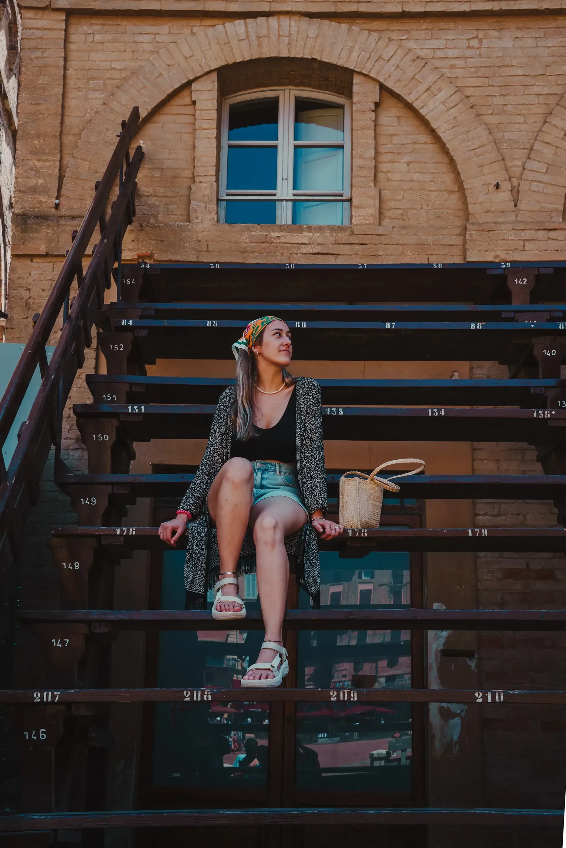 Letizia sitting on the bleachers or stands in Siena's historic square (Piazza del Campo).