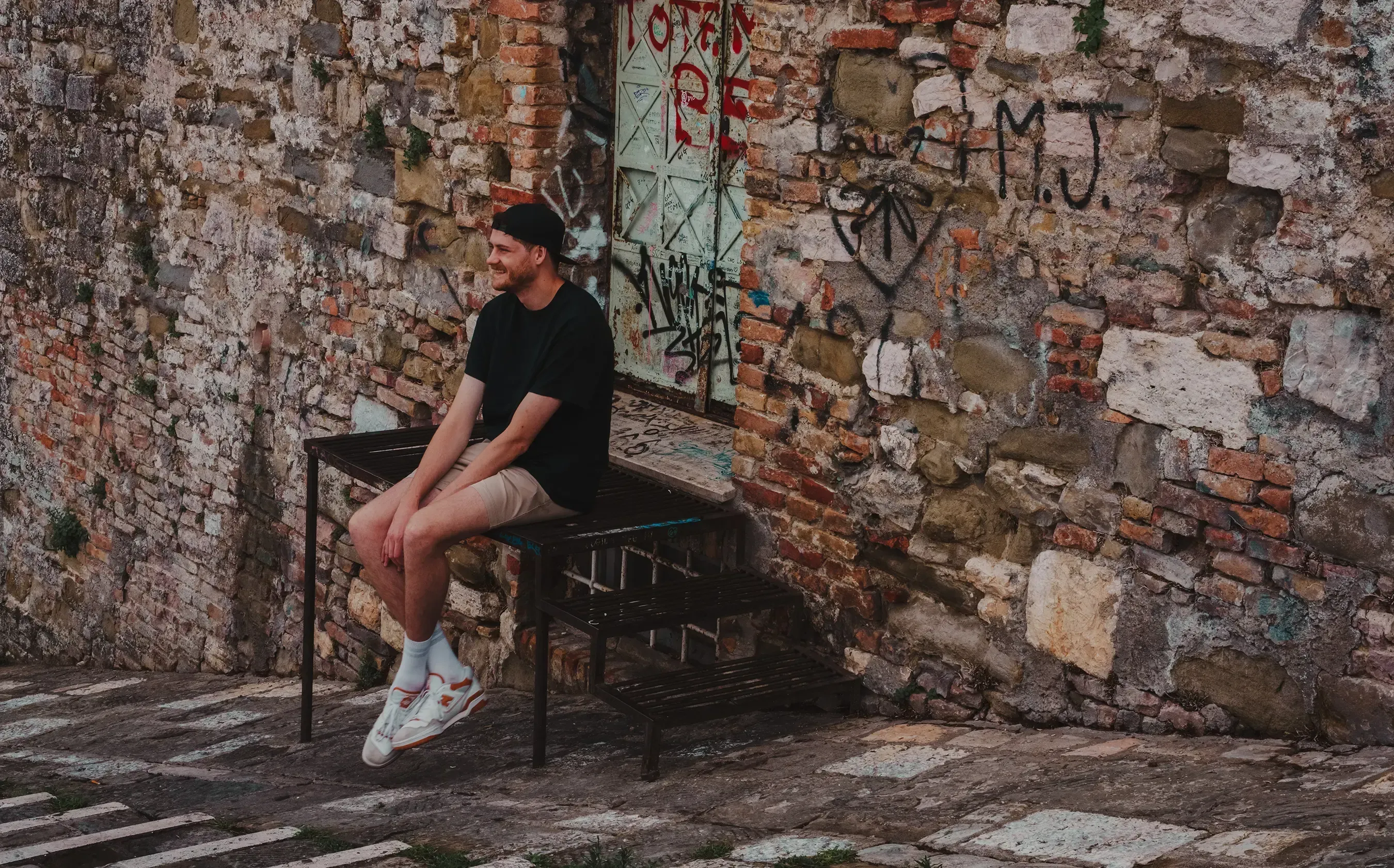 Mattis sitting down in a quiet, narrow stone alleyway in Perugia.
