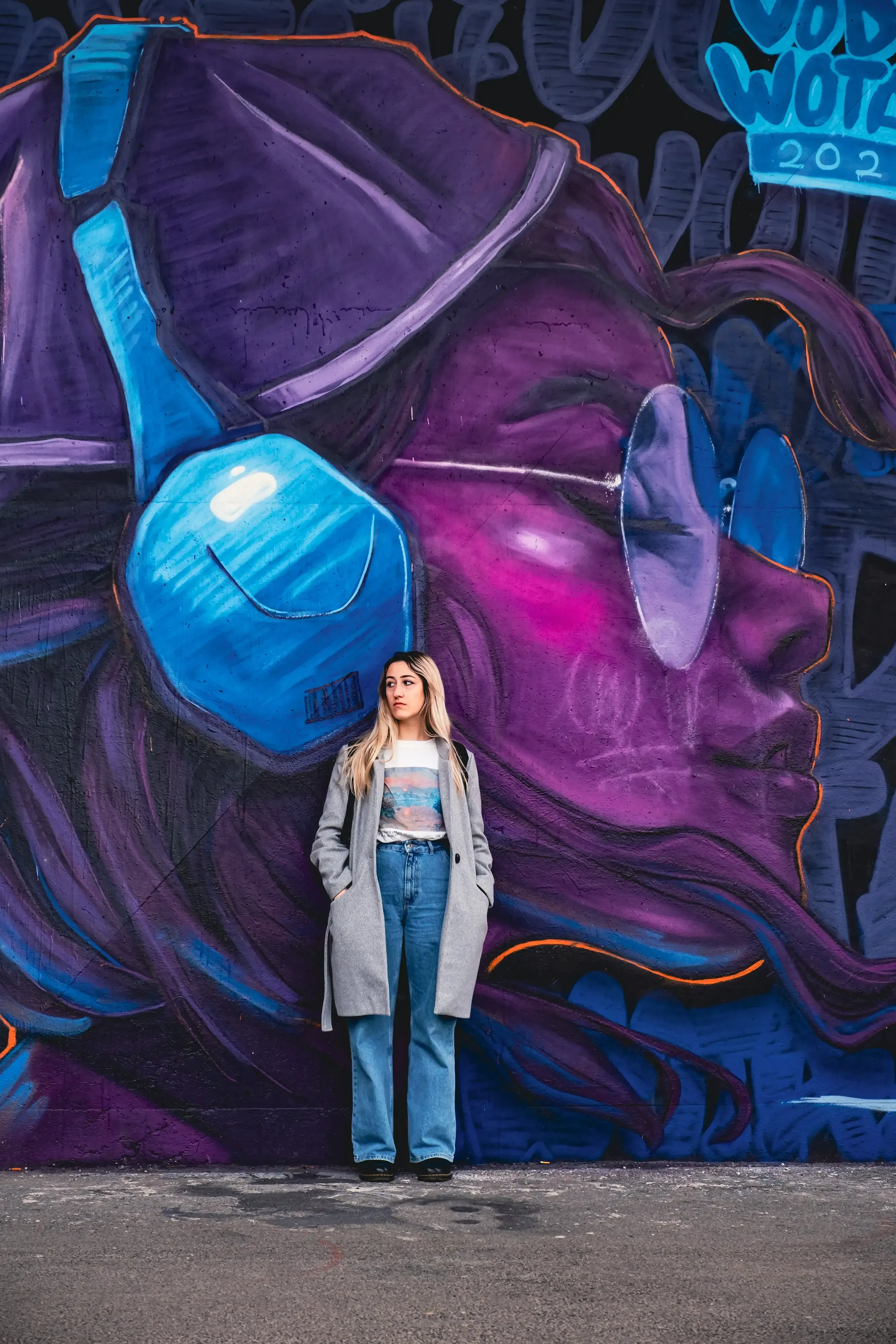 Letizia leaning against a colorful wall covered in graffiti art.
