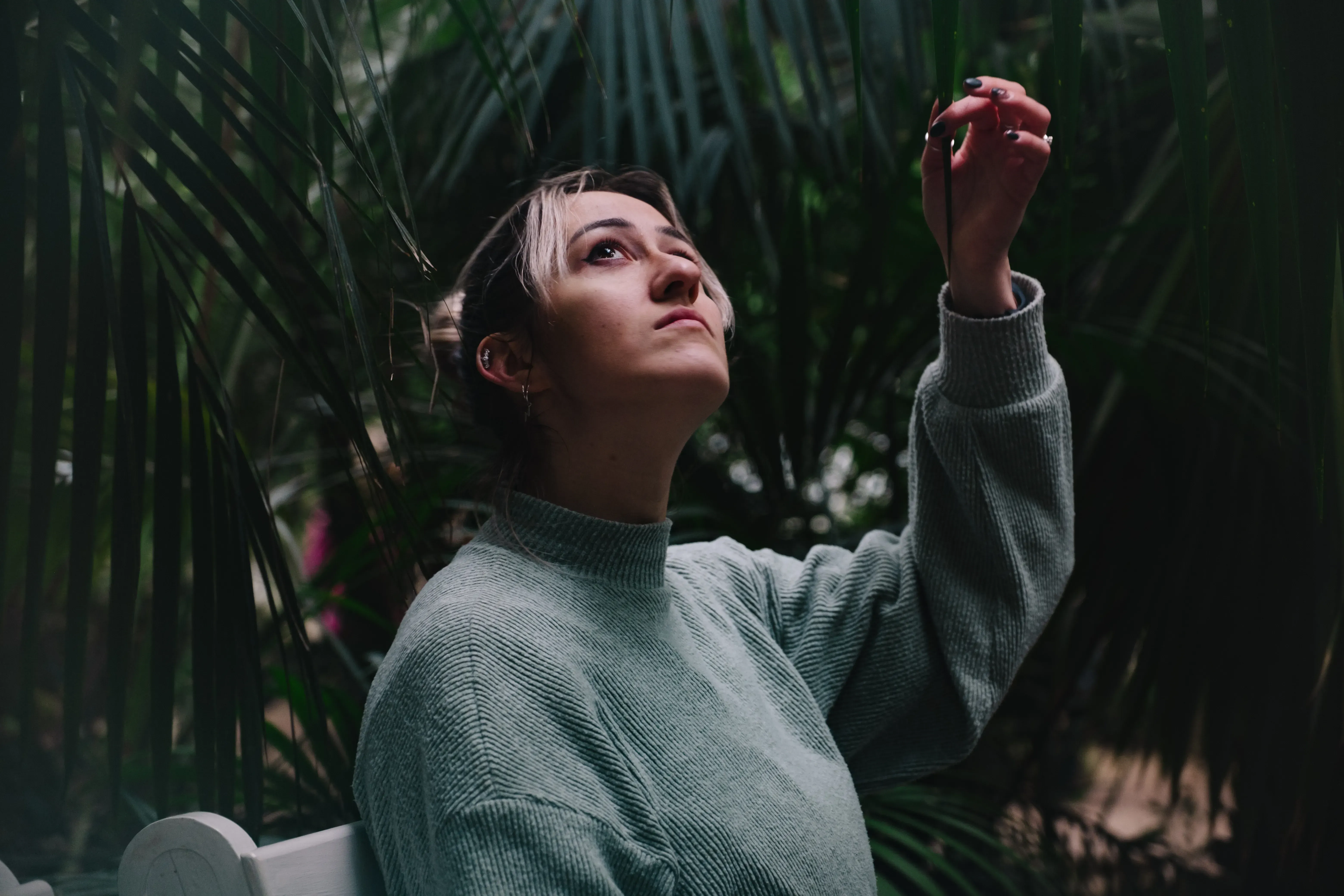 Letizia gently touching the leaves of a tropical plant inside the Palm House.
