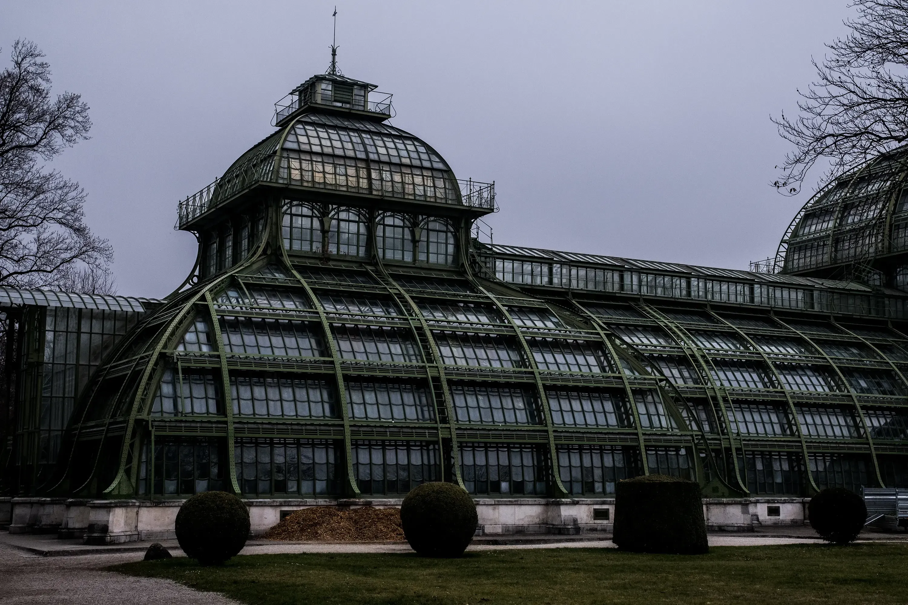 Exterior view of the ornate glass and steel Palmenhaus (Palm House) building in the park.
